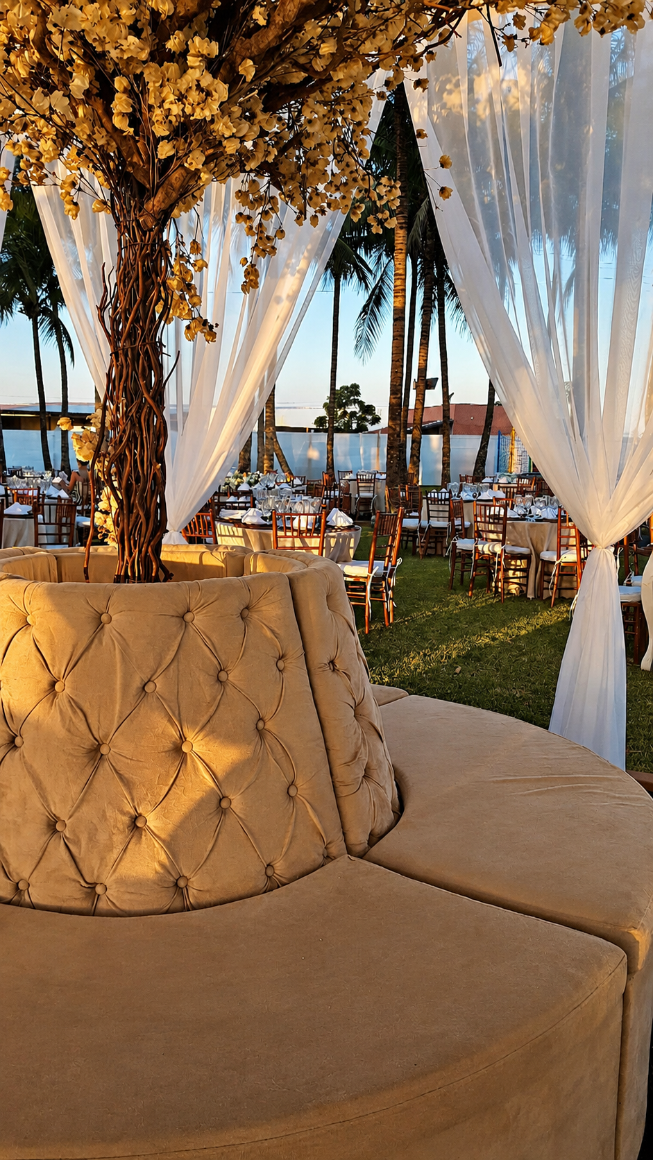 Lounge com sofá capitonê e árvore floral ao entardecer